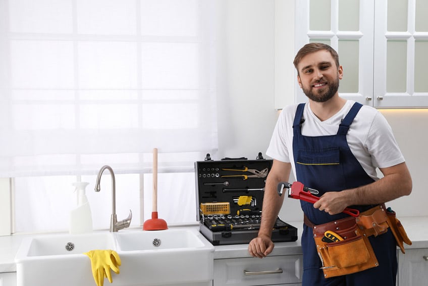 plumber with plunger and instruments near sink in kitchen