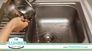 Person Pouring Hot Water Down the Drain